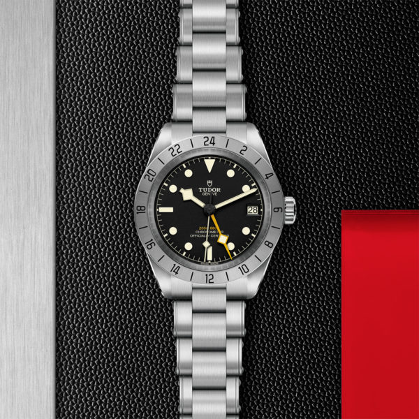 TUDOR Black Bay Pro Watch with 39mm Steel Case, Riveted Steel Bracet (M79470-0001) Flat lay on black and red background