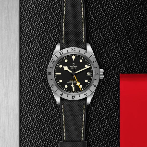 TUDOR Black Bay Pro Watch with a 39mm Steel Case, Hybrid Rubber and Leather Strap (M79470-0003) Flat lay on black and red background