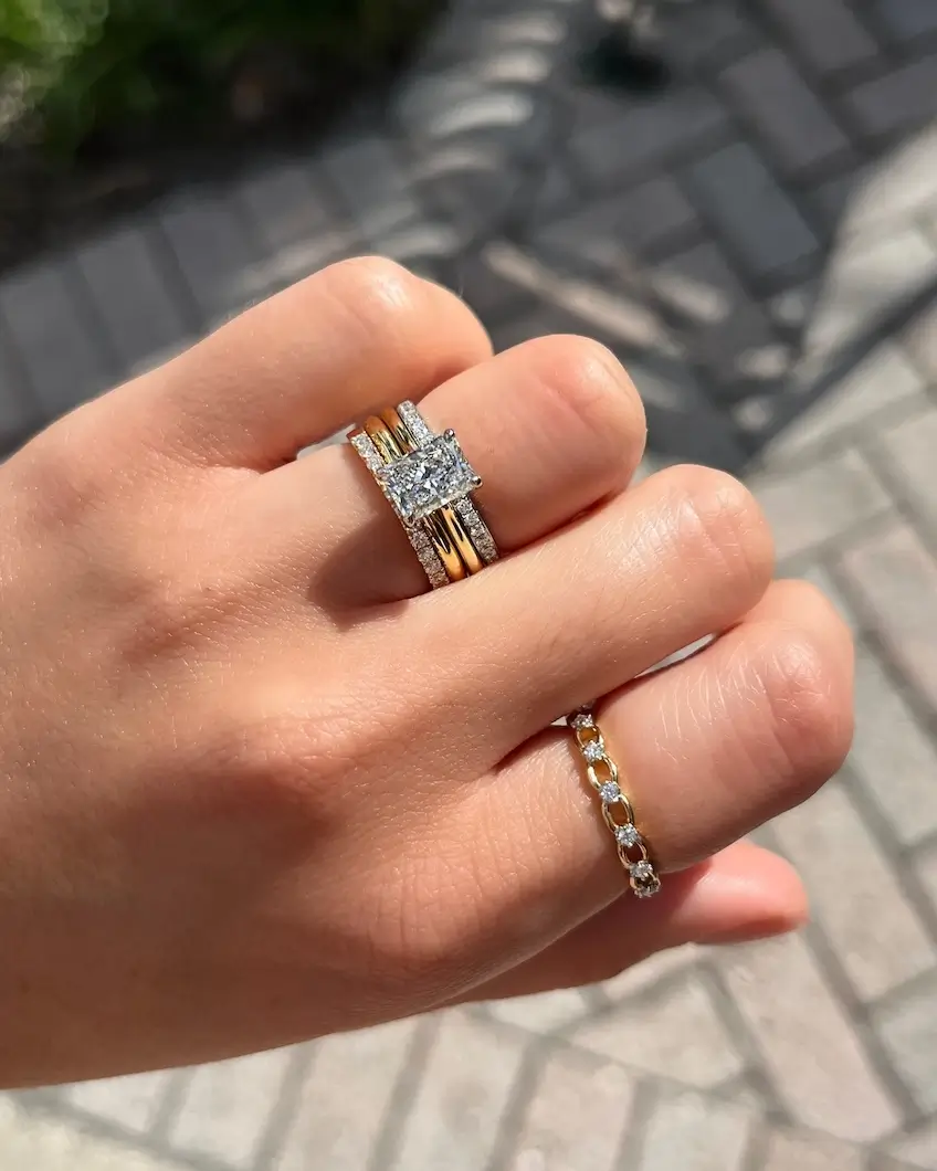 two diamond engagement rings on model's fingers