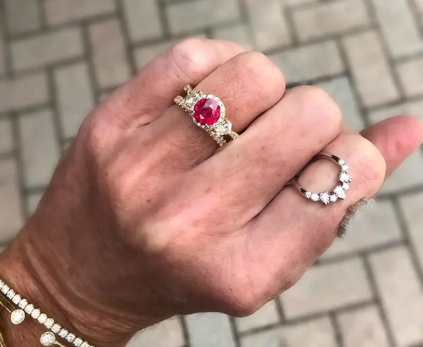 various ruby birthstone pieces on fingers and diamond bracelets on wrist